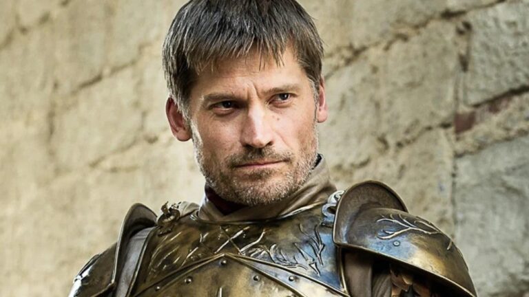 A knight in ornate armor stands against a stone wall, looking intently forward.