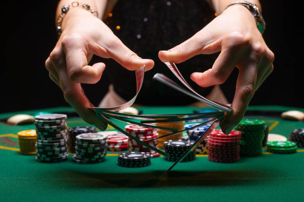 Girl dealer or croupier shuffles poker cards in a casino on the background of a table, chips,. Concept of poker game, game business