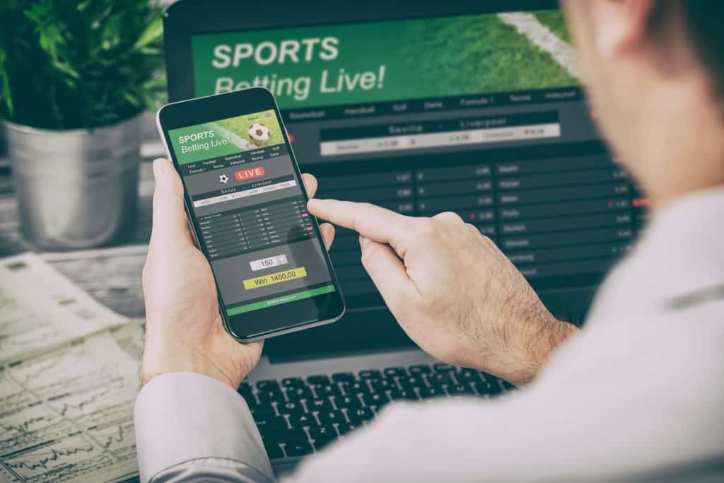 betting bet sport phone gamble laptop over shoulder soccer live home website concept - stock image