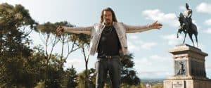 A man with his arms outstretched in front of a statue.