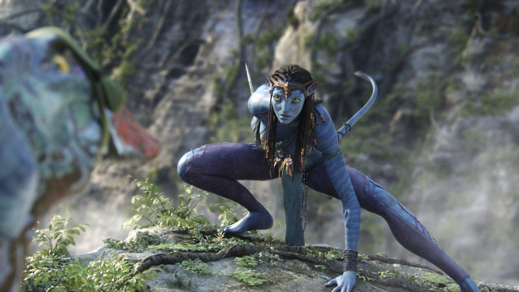 A blue character in avatar is standing on top of a rock.