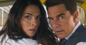 Two people, a woman with long dark hair and a man with short brown hair, look intensely at the camera while sitting closely together.