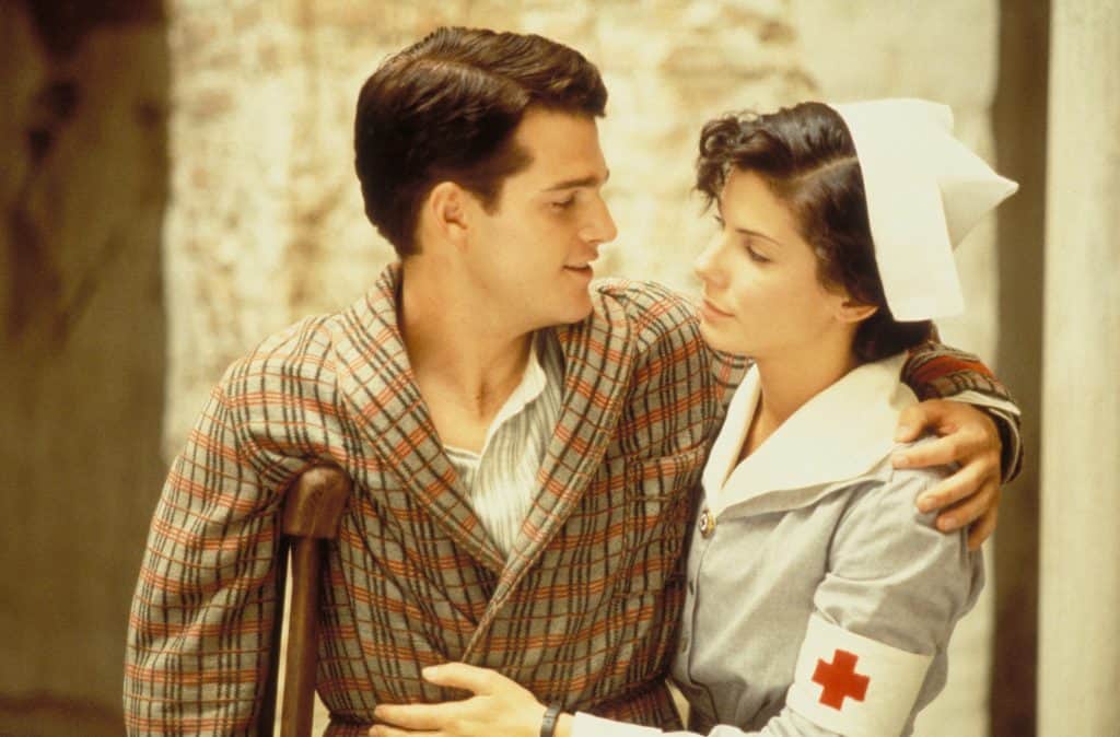 A man and a woman hugging in front of a building.