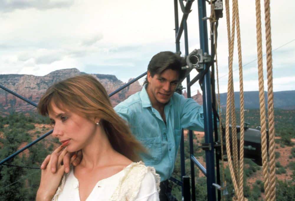 A man and a woman standing on a rope in the mountains.