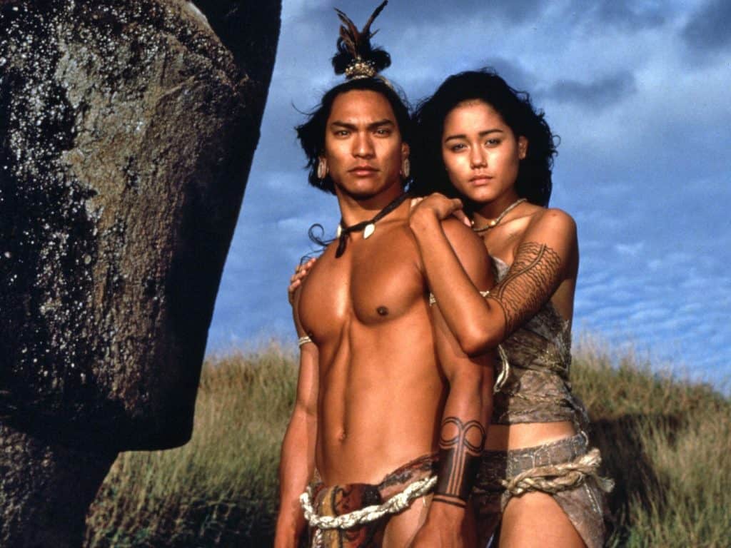 A man and woman posing in front of a large rock.