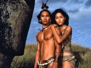 A man and woman posing in front of a large rock.
