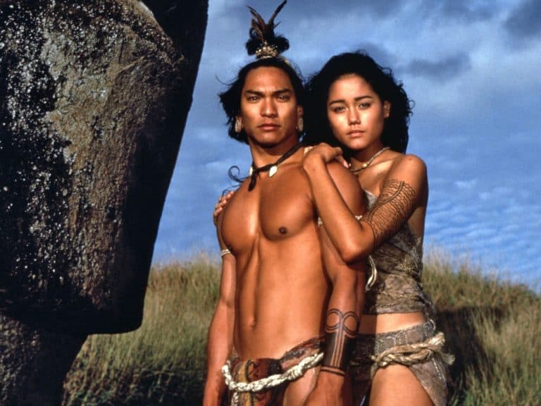 A man and woman posing in front of a large rock.