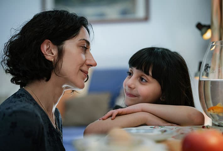 A mother and daughter looking at each other at a table.