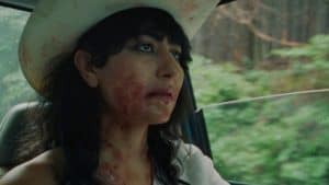 A woman in a cowboy hat with blood on her face.