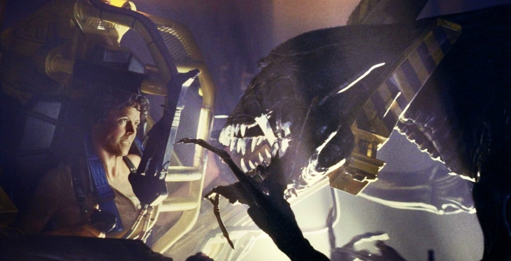A man in a dark room with a giant alien in front of him.