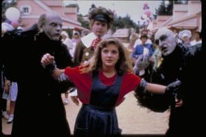 A girl dressed as a witch is standing next to a group of people.