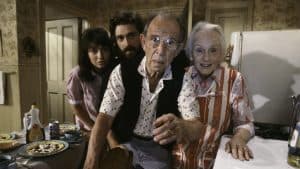 A group of people in a kitchen with food on the table.