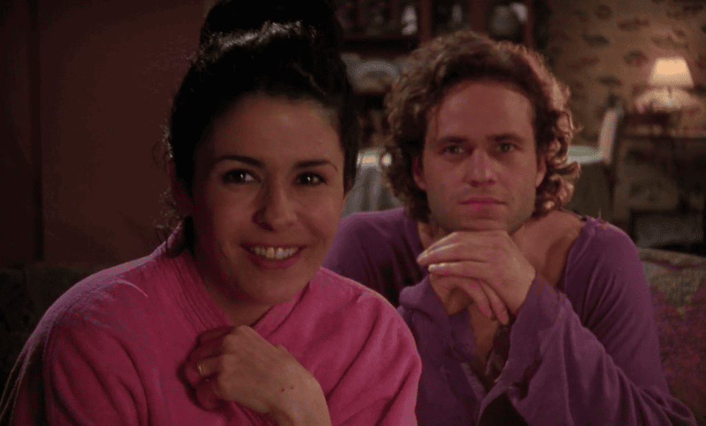 A man and woman in purple robes sitting on a couch.