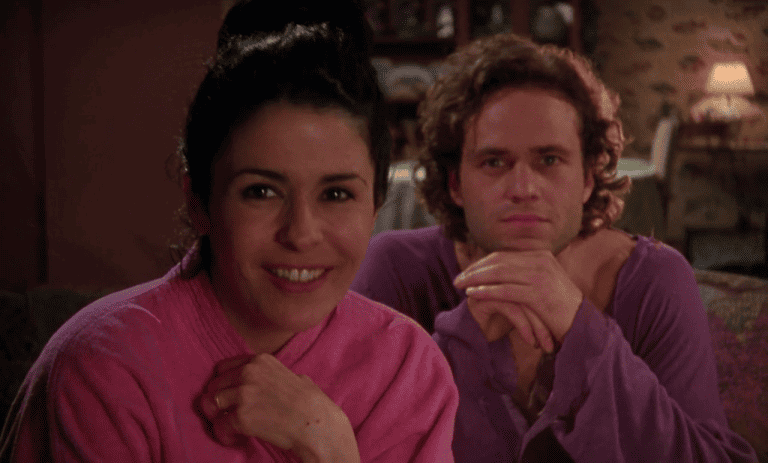 ‘Caught’ (1996) Blu-Ray Review – Domestic Drama Bubbles With Lust & Bad Decisions A man and woman in purple robes sitting on a couch.