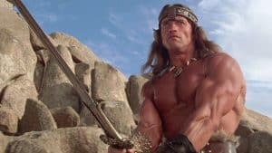 A man holding a sword in front of rocks.