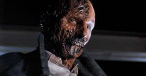 ‘Darkman’ 4K UHD Blu-Ray Review – Sam Raimi Crafts A Darkly Looney Superhero Tale A man with a bloody face is standing in a dark room.
