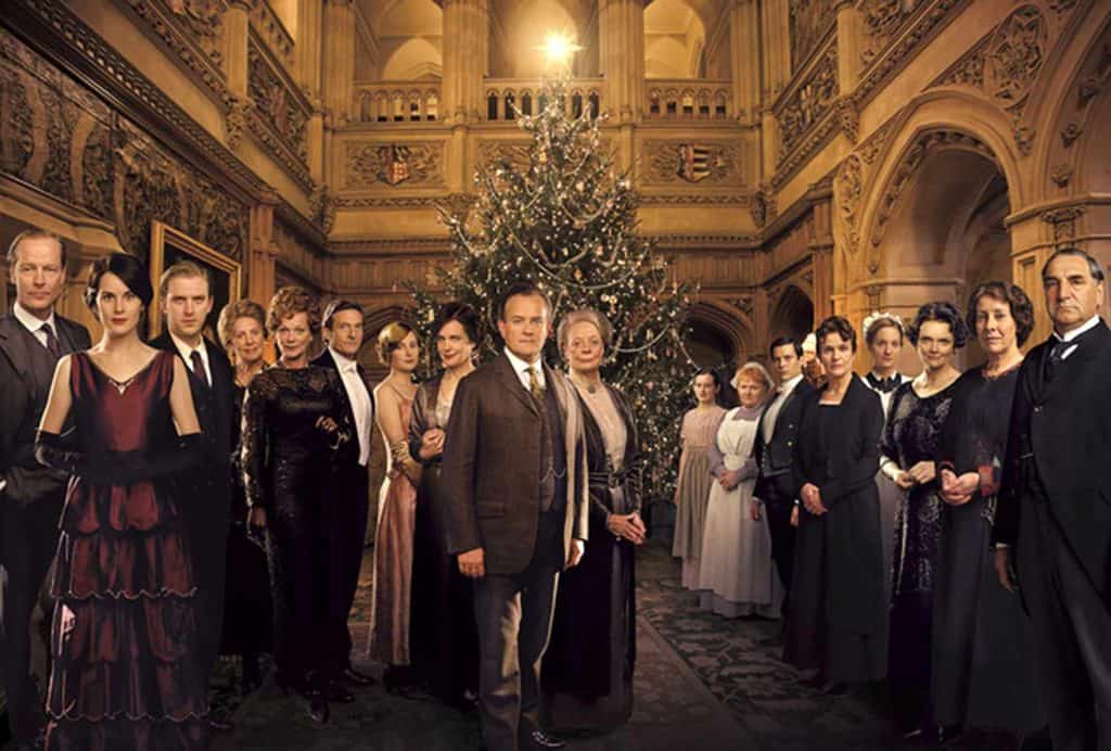 The cast of downton abbey in front of a christmas tree.