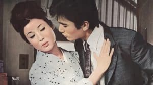 A man and woman kissing in front of a poster.