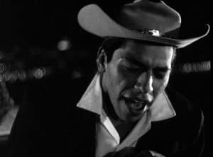 A man in a cowboy hat with a microphone.
