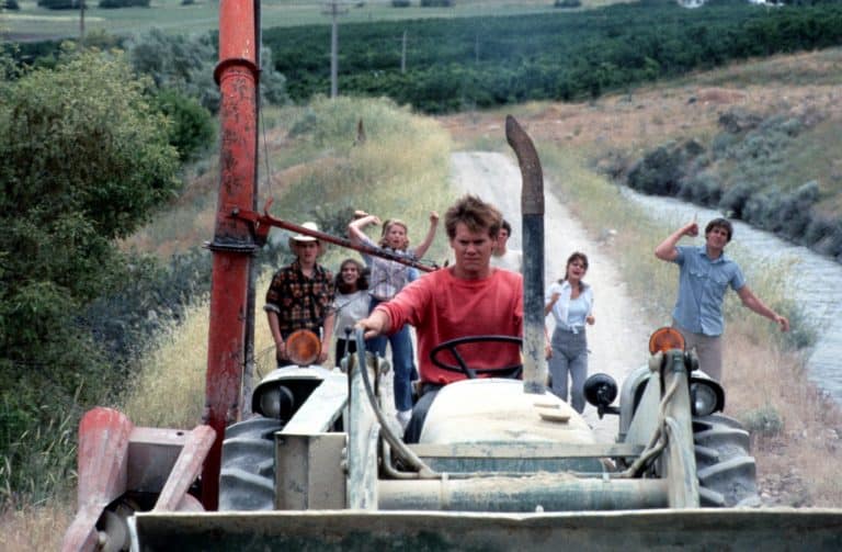 A group of people riding a tractor on a dirt road.