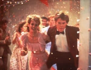 Paramount To Celebrate The 40th Anniversary Of ‘Footloose’ With A 4K UHD Blu-Ray This February A man and woman in a dress and tuxedo running through confetti.