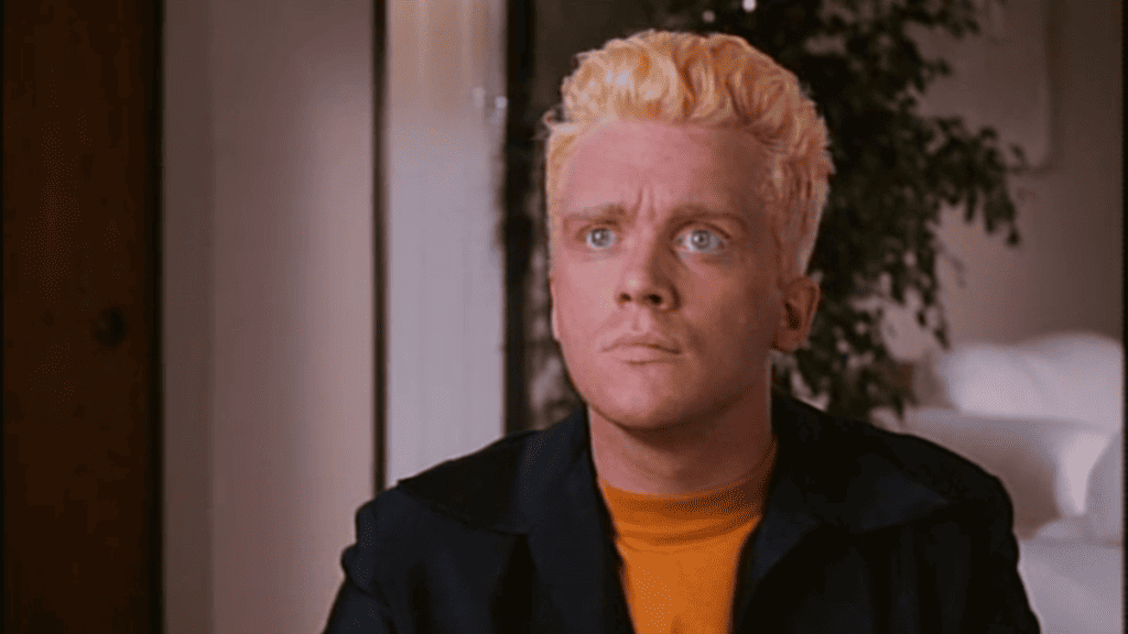 A man with blonde hair sitting in a room.