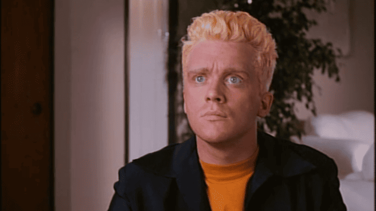A man with blonde hair sitting in a room.