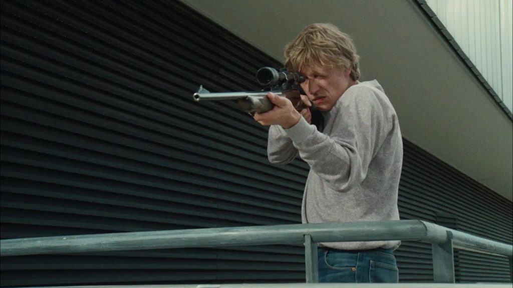 A man holding a gun on a railing.