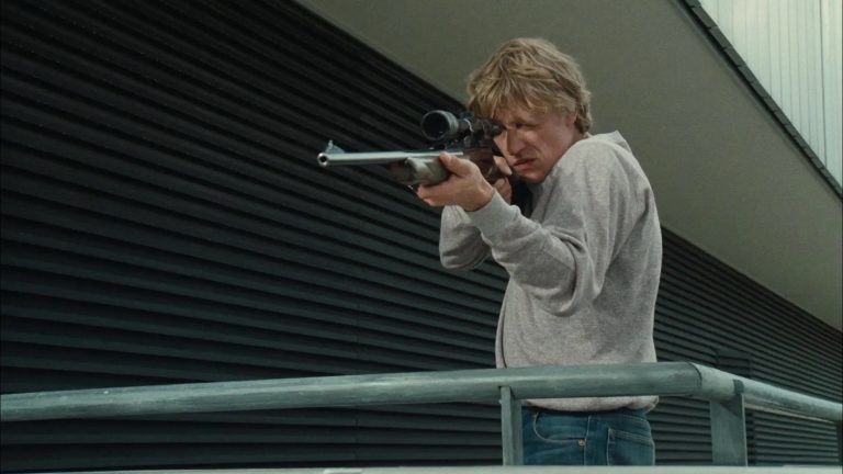 ‘I… For Icarus’ Blu-Ray Review – A Riveting Paranoid Thriller Not To Be Missed A man holding a gun on a railing.