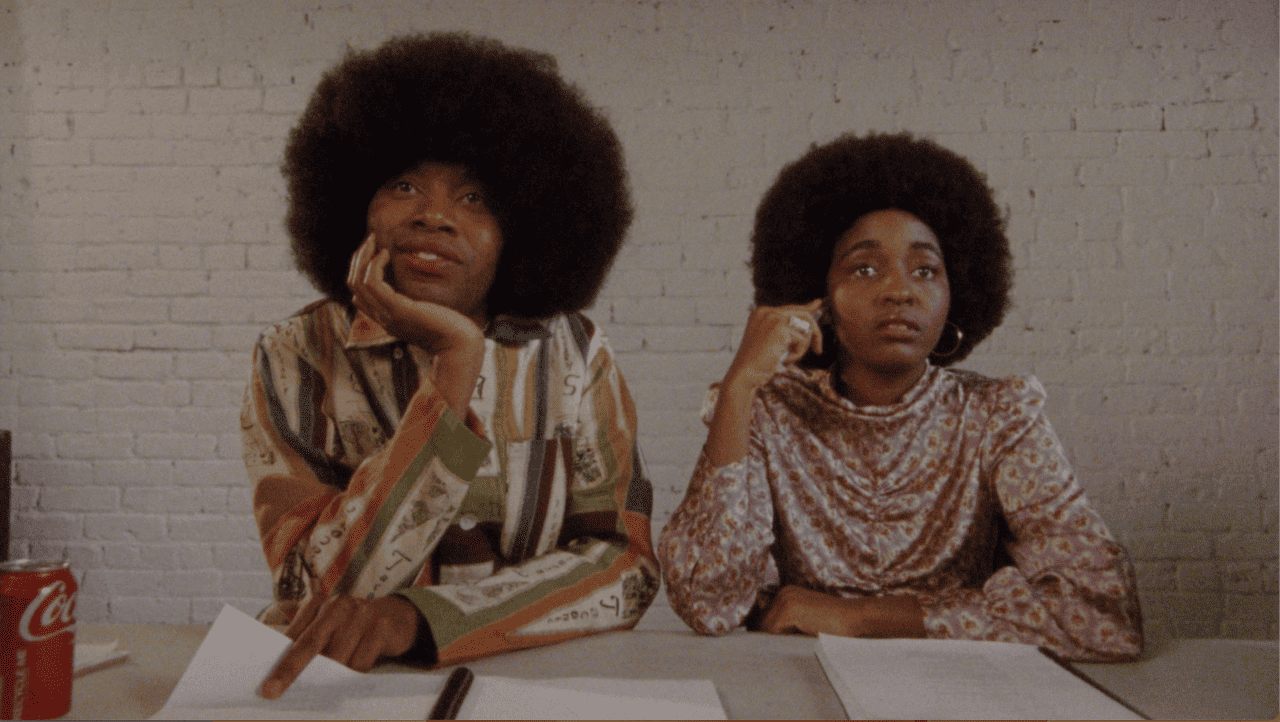 Two people with afros sitting at a table.