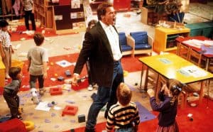 A man in a suit standing in front of a group of children.