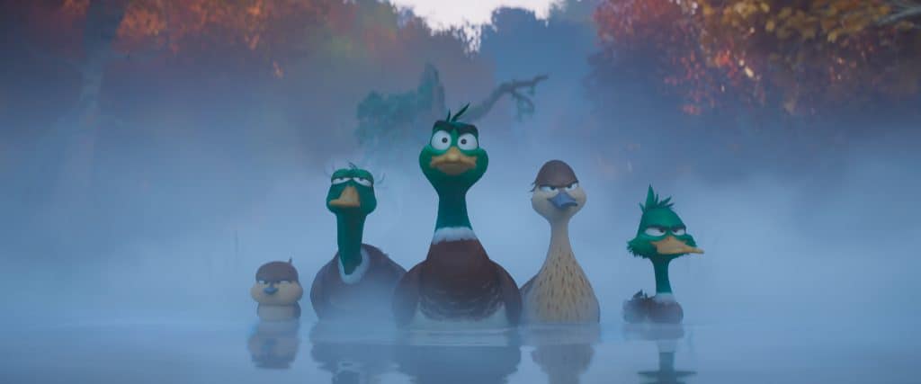 A group of ducks in a foggy lake.