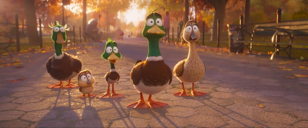 A group of ducks are walking down a street.