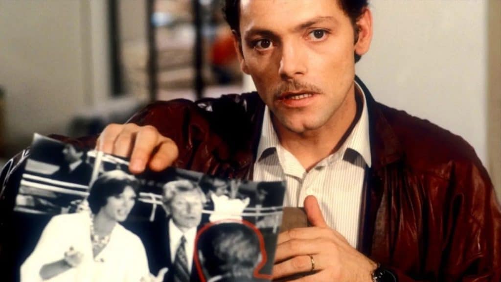 A man holding up a picture of a man and a woman.
