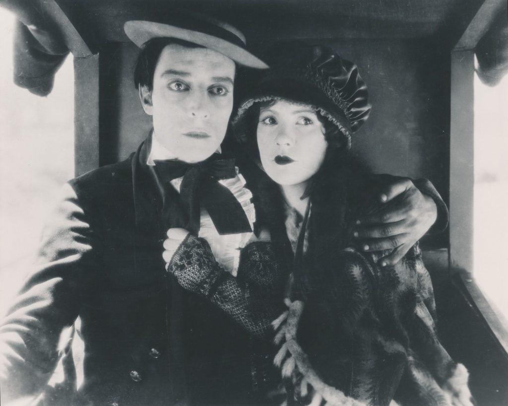 A black and white photo of a man and woman on a train.