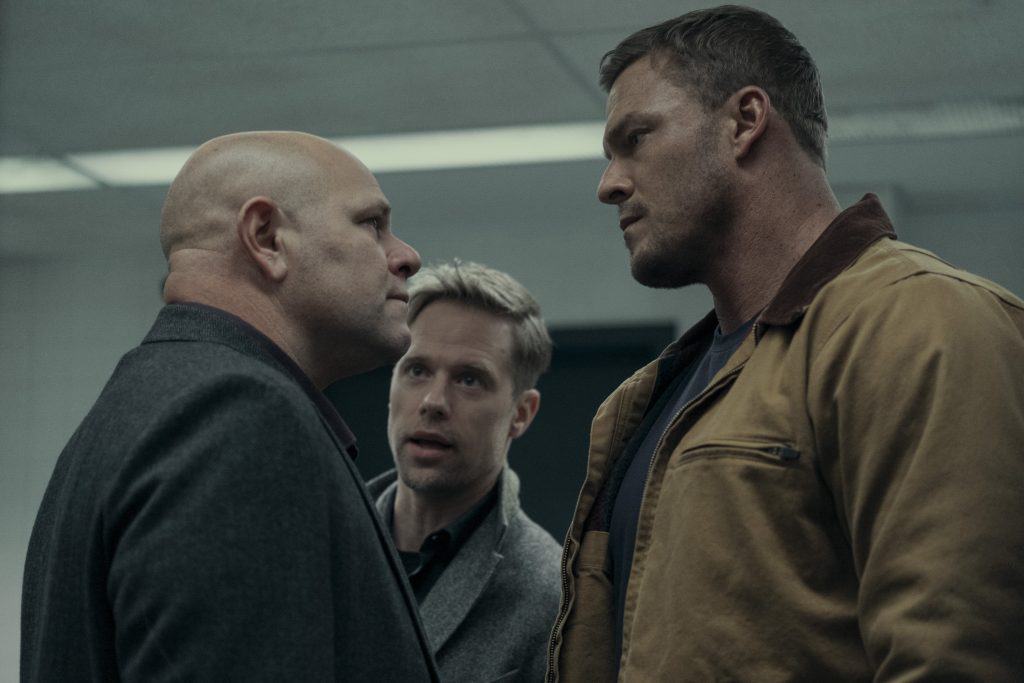 Three men are talking to each other in an office.