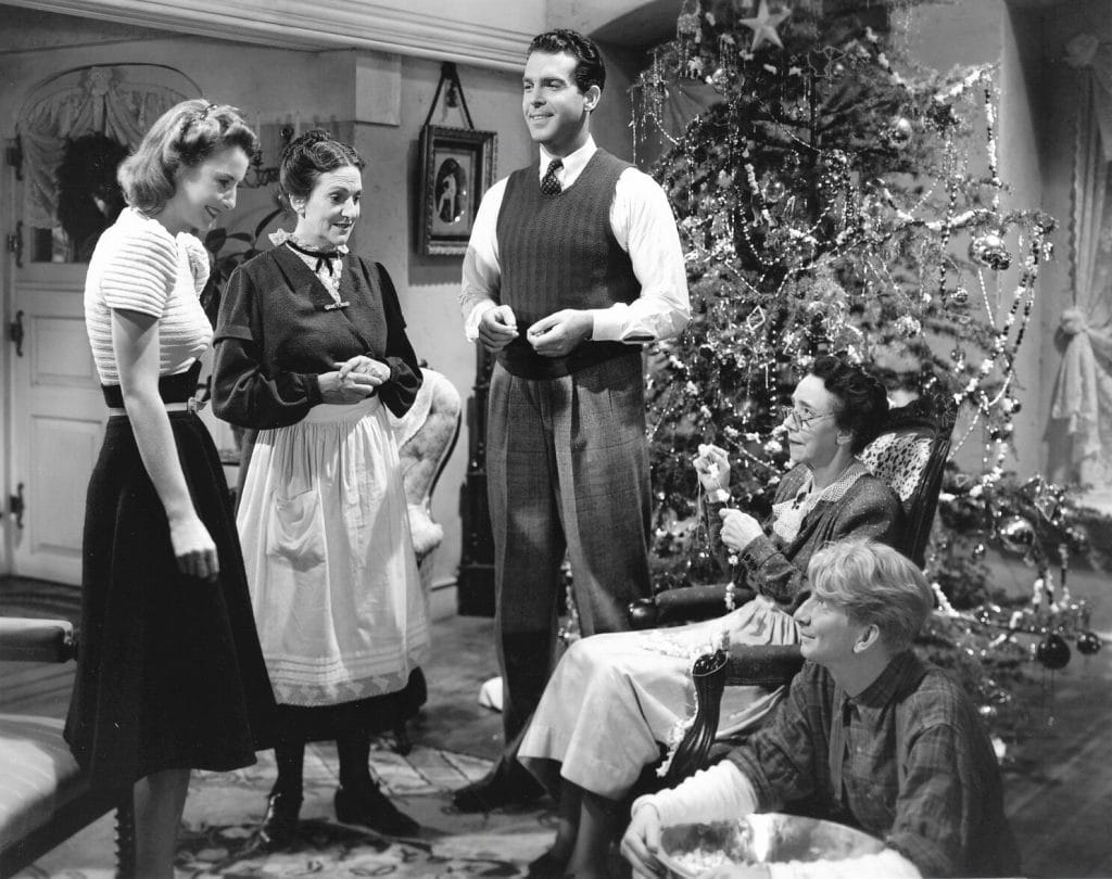 A group of people standing around a christmas tree.