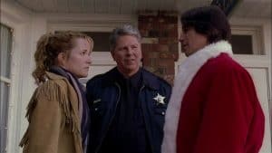 Three people in santa claus costumes talking to each other.