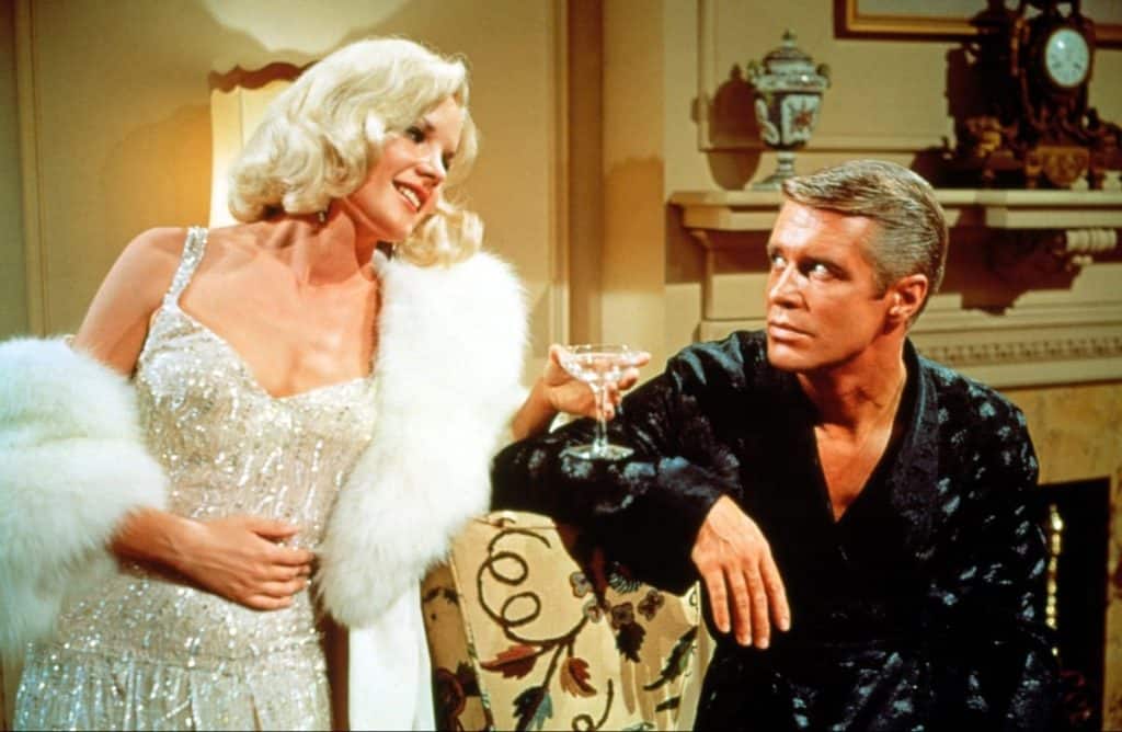 A man and a woman in a robe holding a glass of wine.