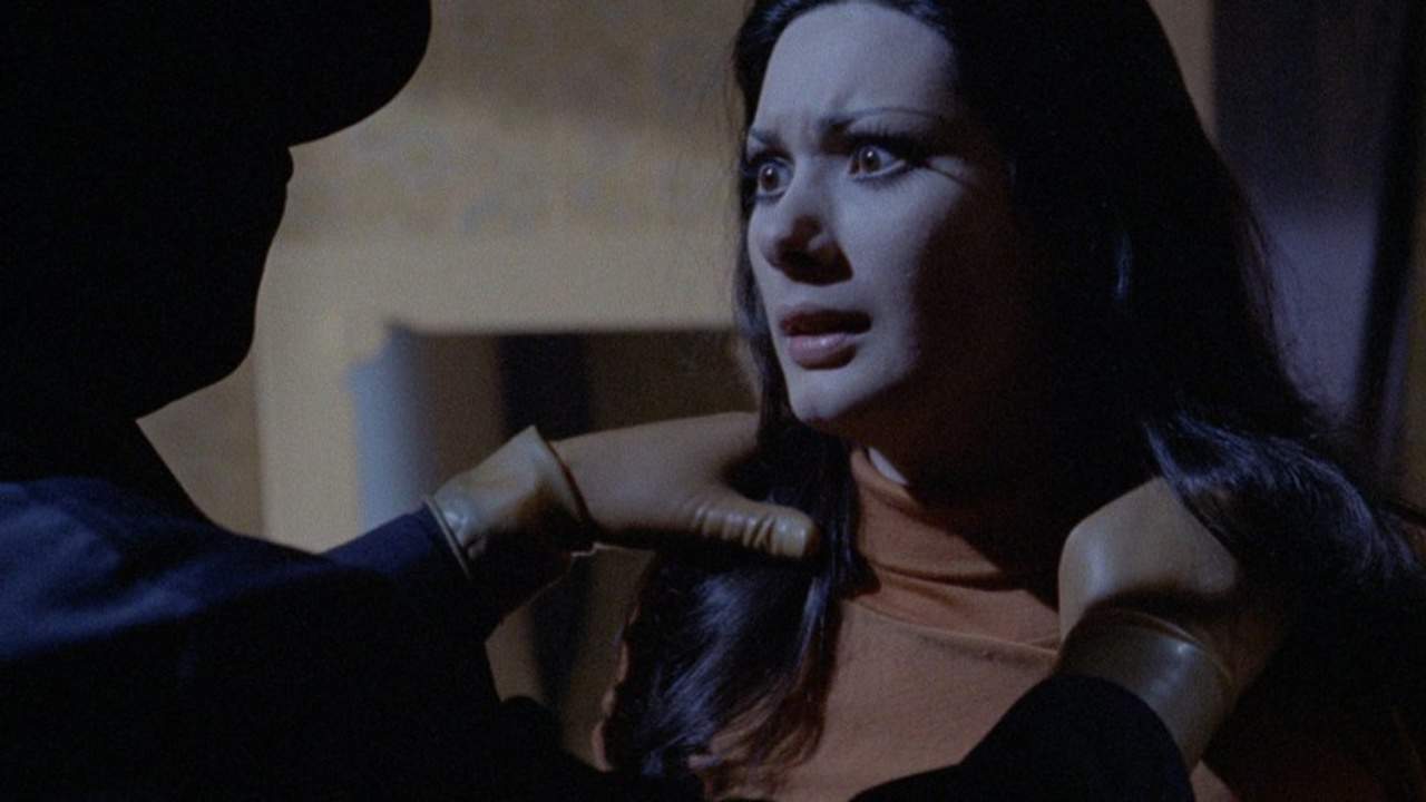 A woman in an orange shirt is being touched by a man.