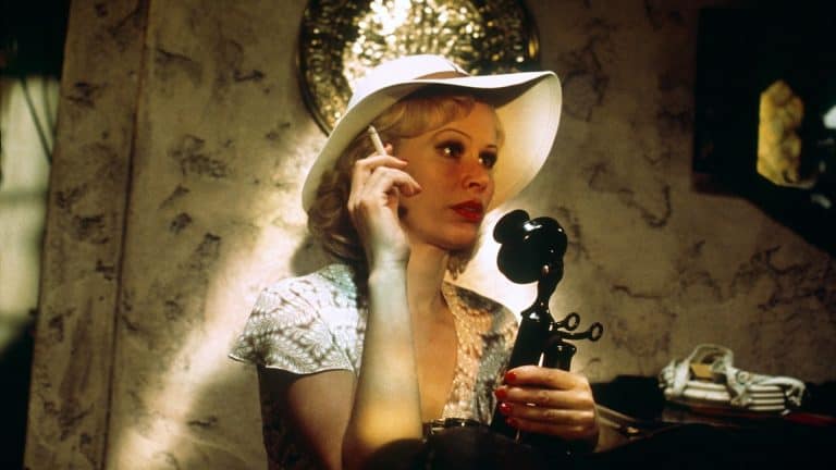 ‘The Day Of The Locust’ Arrow Video Blu-Ray Review – Exploring The Dark Underbelly Of Old Hollywood A woman in a white hat talking on the phone.