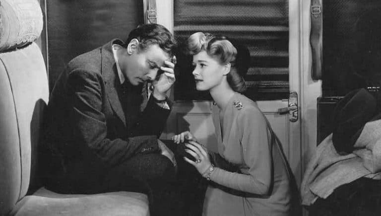 A man and woman sitting on a couch looking at each other.
