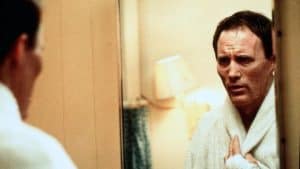 A man in a bathrobe looking at himself in a mirror.