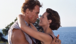 A man and woman hugging in front of the ocean.