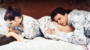 A man and woman laying on a bed.