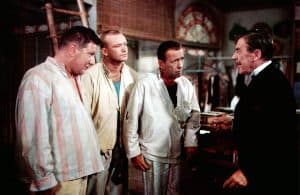 ‘We’re No Angels’ (1955) Blu-Ray Review – Humphrey Bogart Leads Atypical Christmas Comedy A group of men in a room talking to each other.