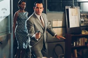 OSS 117 Collection Blu-Ray Review – Spy Spoof Franchise Takes Its Assignment Seriously A man in a suit is holding a gun.