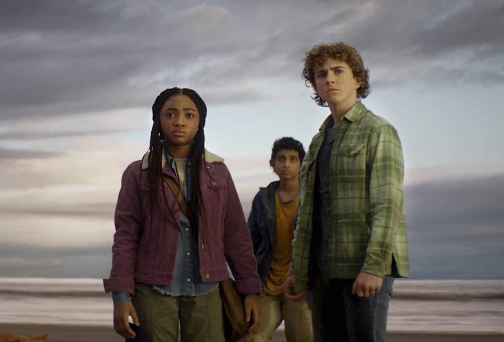 A group of people standing on the beach in front of a cloudy sky.