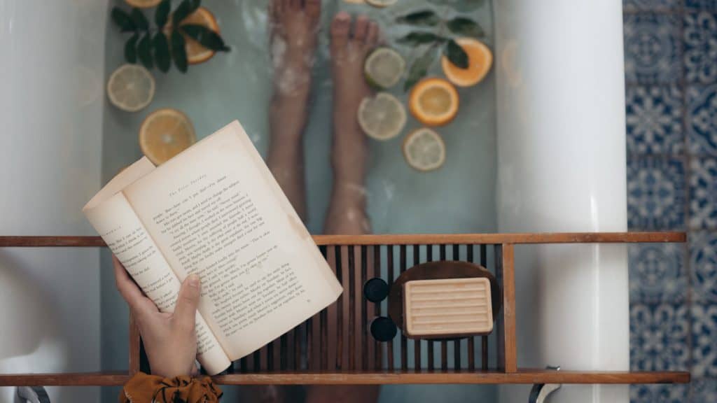 A woman is reading a book while sitting in a bathtub.