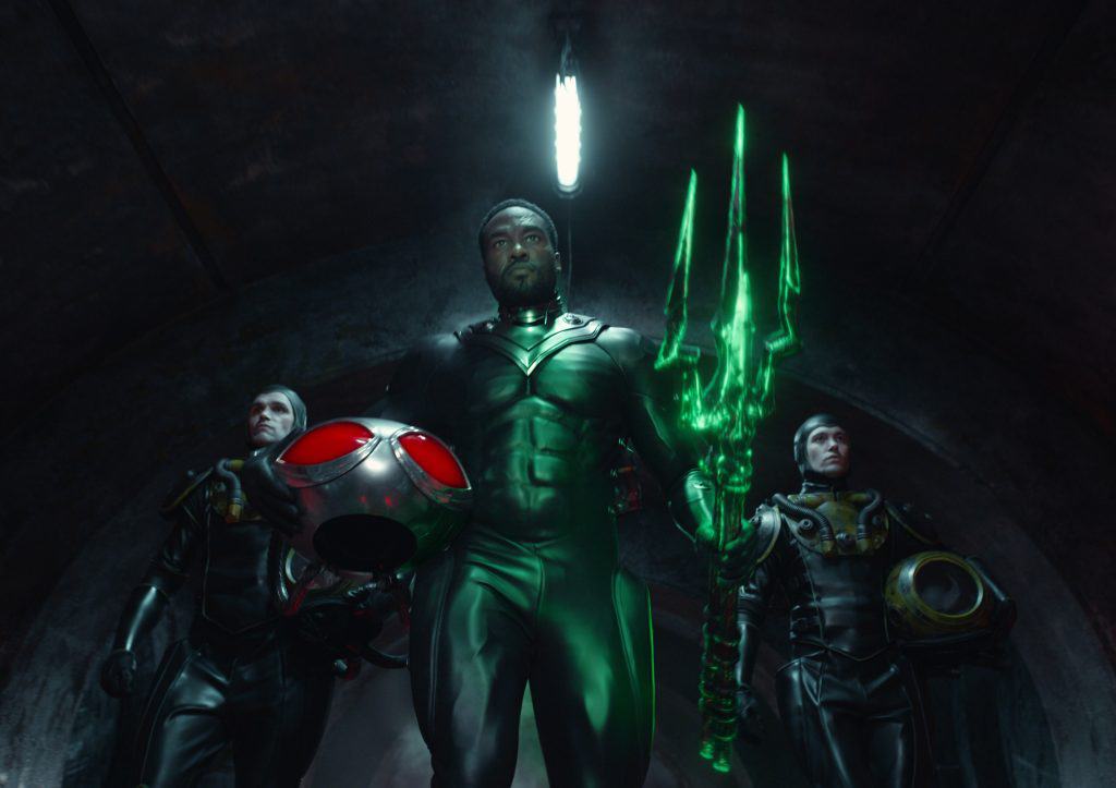 A group of men in green suits standing in a tunnel.